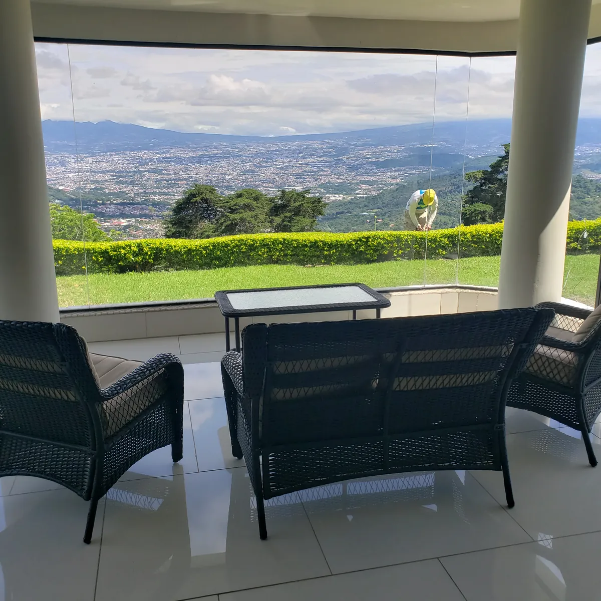 Covered terrace seating behind a glass railing, looking over the green hills and the San José valley