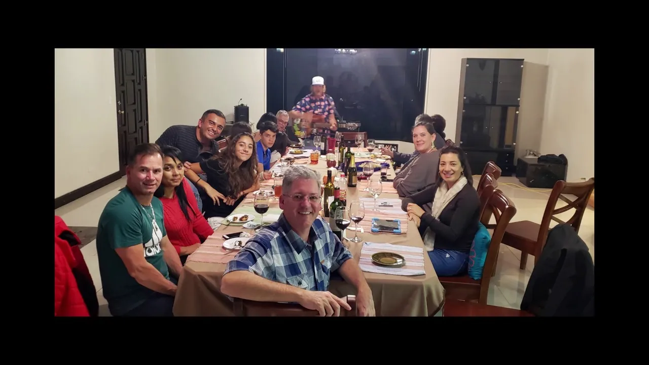 Friends sharing dinner at the long dining table inside the Pura Vida World home